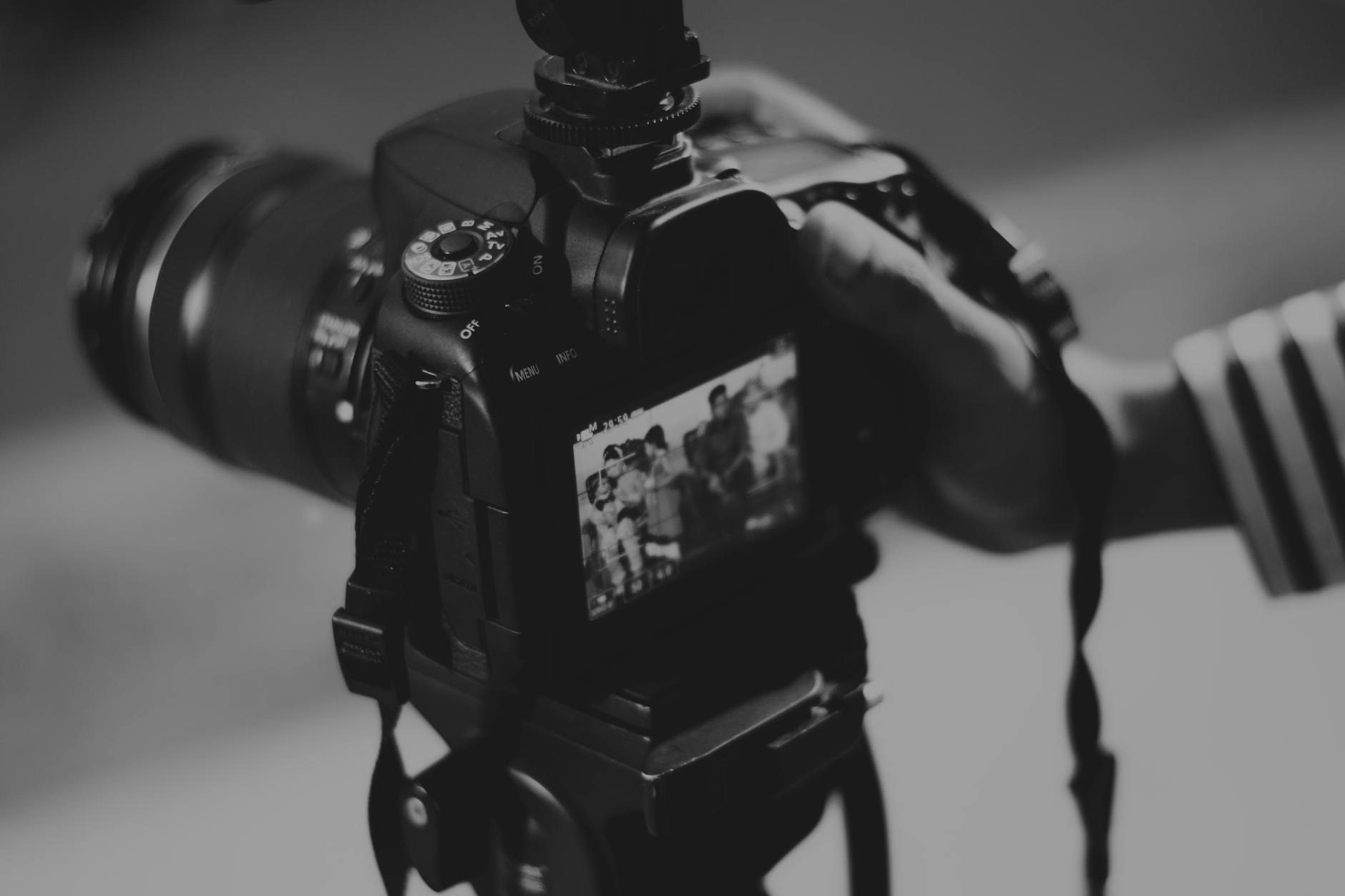 grayscale photography of person holding black dslr camera