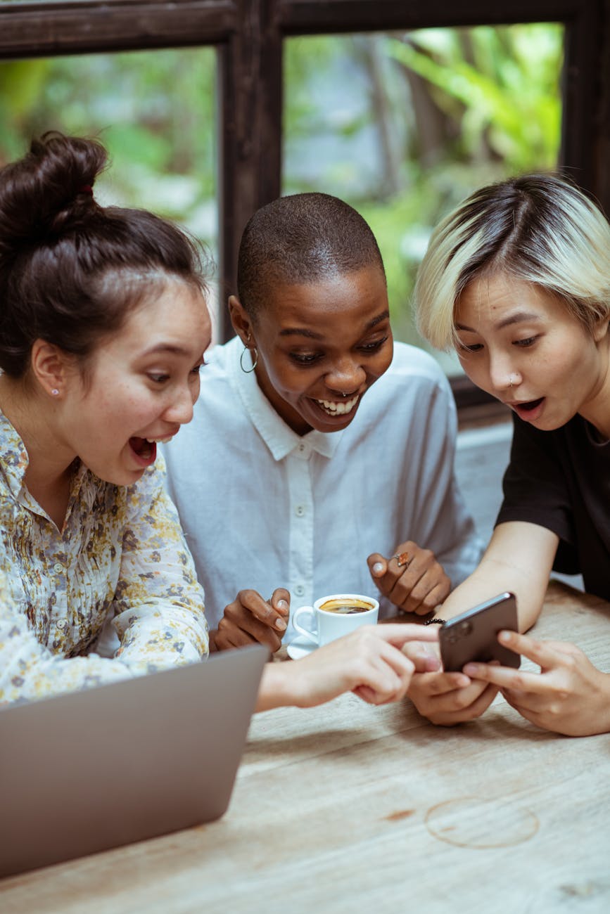 delighted female friends with laptop and smartphone